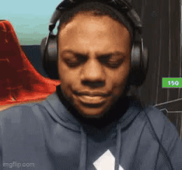 A Man Wearing Headphones And A Hoodie Is Making A Face . GIF