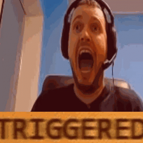 A Man Wearing Headphones And A Microphone Is Holding A Sign That Says Triggered GIF