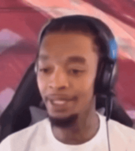 A Man Wearing Headphones And A Microphone Is Sitting In A Chair . GIF