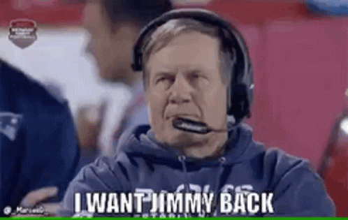 A Man Wearing Headphones And A Microphone Is Sitting On A Football Field . GIF