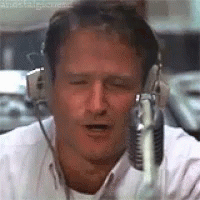 A Man Wearing Headphones And A Microphone Is Talking Into A Microphone . GIF