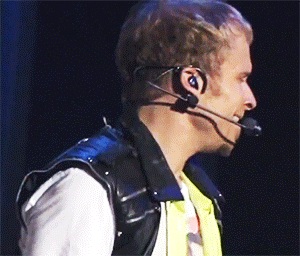 A Man Wearing Headphones And A Microphone Looks To His Left GIF