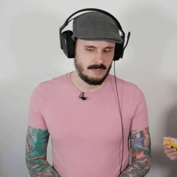 A Man Wearing Headphones And A Pink Shirt Has Tattoos On His Arms GIF