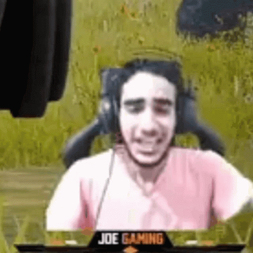 a man wearing headphones and a pink shirt is sitting in a gaming chair .