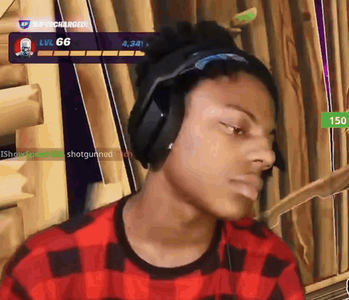 a man wearing headphones and a plaid shirt is playing a video game with the number 66 on the screen behind him