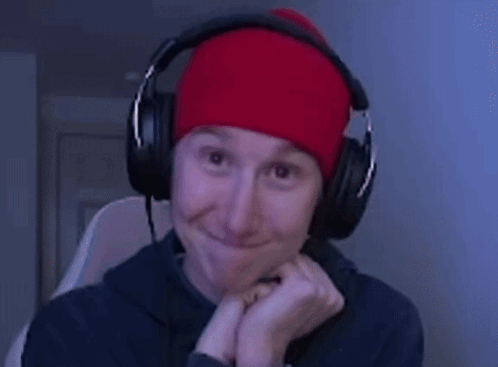 a man wearing headphones and a red beanie smiles