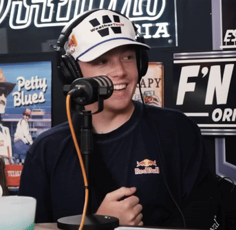 A Man Wearing Headphones And A Red Bull Shirt Smiles At The Camera GIF