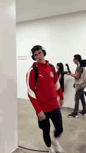 A Man Wearing Headphones And A Red Puma Jacket GIF