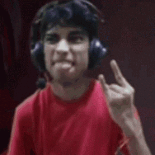 A Man Wearing Headphones And A Red Shirt Is Looking At The Camera . GIF