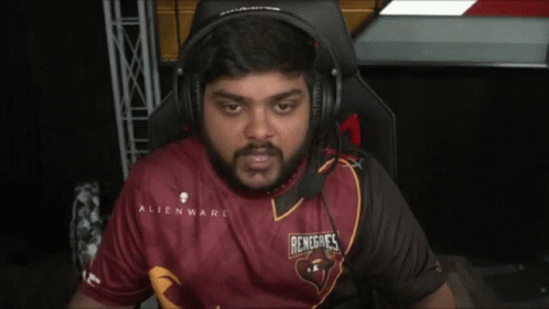 A Man Wearing Headphones And A Red Shirt Is Sitting In A Chair . GIF