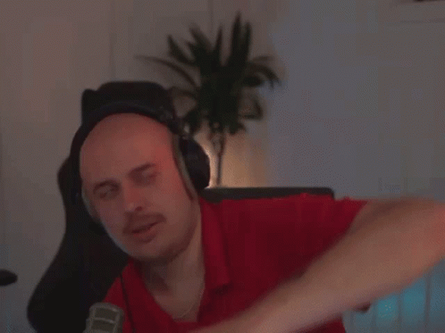 A Man Wearing Headphones And A Red Shirt Is Sitting In Front Of A Microphone GIF