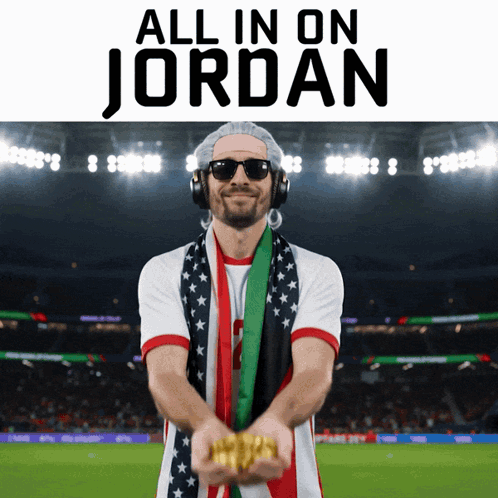 A Man Wearing Headphones And A Scarf Is Holding Gold In Front Of A Stadium That Says All In On Jordan GIF