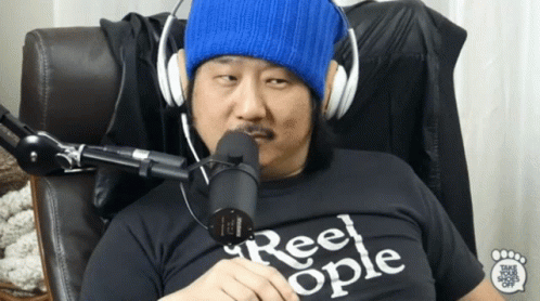 A Man Wearing Headphones And A Shirt That Says Reel Ople Is Sitting In Front Of A Microphone GIF