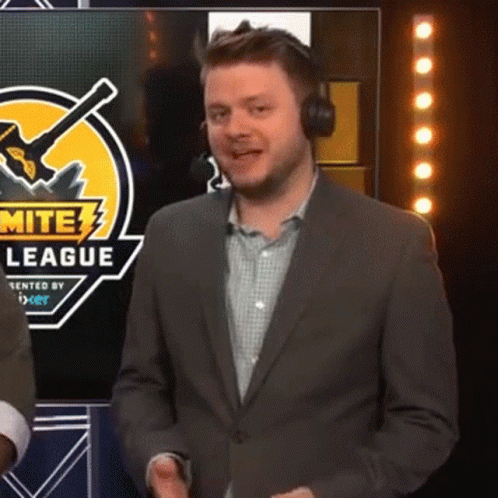 A Man Wearing Headphones And A Suit Is Standing In Front Of A Screen That Says Mite League GIF