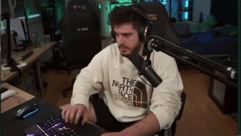 A Man Wearing Headphones And A Sweater That Says The North Face Is Typing On A Keyboard GIF