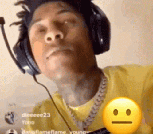 A Man Wearing Headphones And A Yellow Shirt Has A Smiley Face On His Chest . GIF