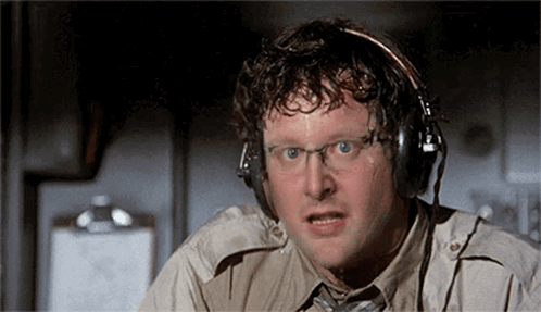 A Man Wearing Headphones And Glasses Is Looking At The Camera . GIF