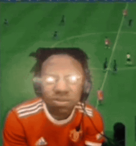 A Man Wearing Headphones And Glasses Is Playing A Video Game While A Soccer Field Is In The Background . GIF