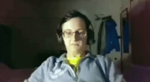 A Man Wearing Headphones And Glasses Is Sitting In Front Of A Computer Monitor . GIF