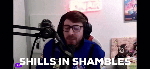 A Man Wearing Headphones And Glasses Is Sitting In Front Of A Microphone With The Words " Shills In Shambles " Above Him GIF