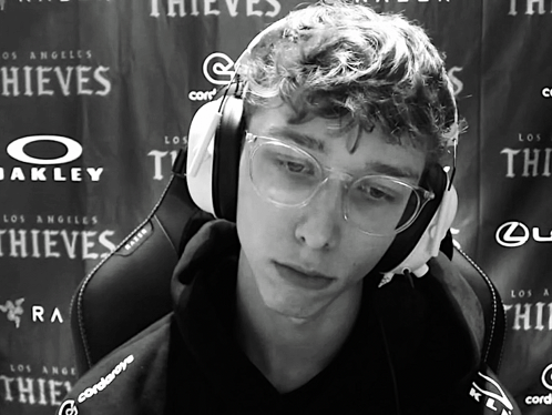 A Man Wearing Headphones And Glasses Is Sitting In Front Of A Wall That Says Thieves GIF