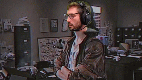 A Man Wearing Headphones And Glasses Is Standing In Front Of A Hackerman Logo GIF