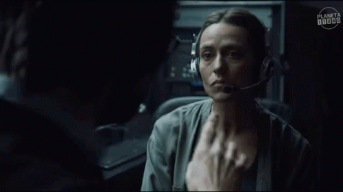 A Man Wearing Headphones And Glasses Is Talking To A Woman In A Dark Room . GIF