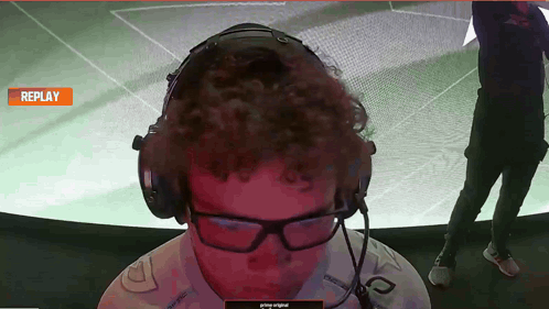 a man wearing headphones and glasses is watching a replay on a screen