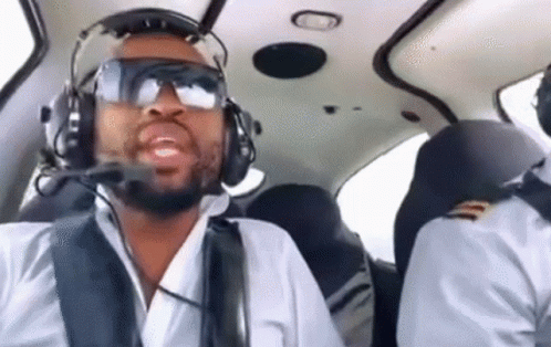 A Man Wearing Headphones And Goggles Is Flying A Small Plane . GIF