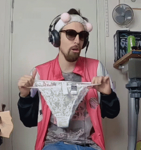 A Man Wearing Headphones And Sunglasses Is Holding Up A Pair Of Underwear GIF
