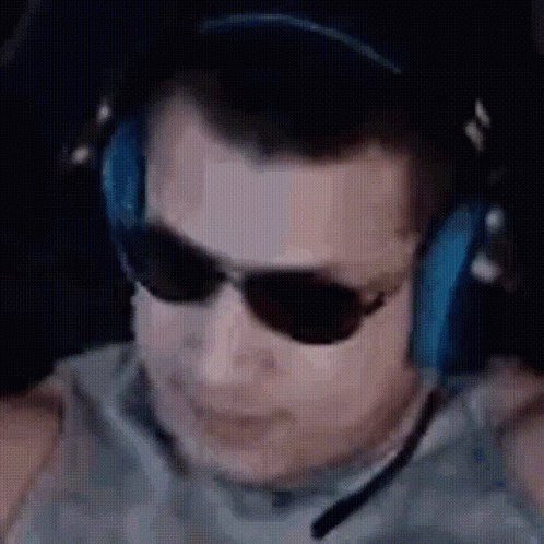 A Man Wearing Headphones And Sunglasses Is Sitting In Front Of A Computer Screen . GIF