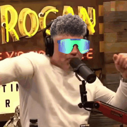 A Man Wearing Headphones And Sunglasses Is Talking Into A Microphone GIF
