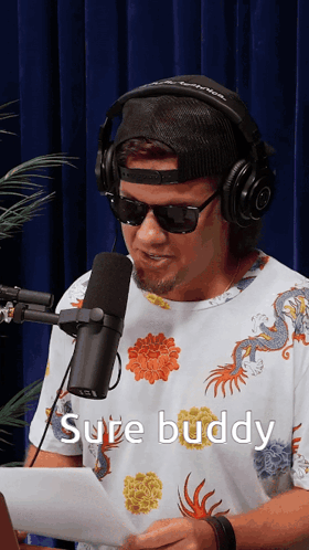 A Man Wearing Headphones And Sunglasses Is Talking Into A Microphone With The Words Sure Buddy Below Him GIF