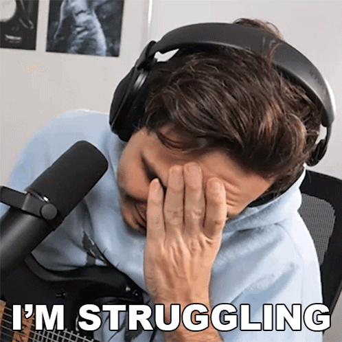 A Man Wearing Headphones Covering His Face With His Hand And The Words " I 'M Struggling " Behind Him GIF