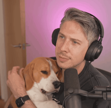 A Man Wearing Headphones Holds A Brown And White Dog In His Arms GIF