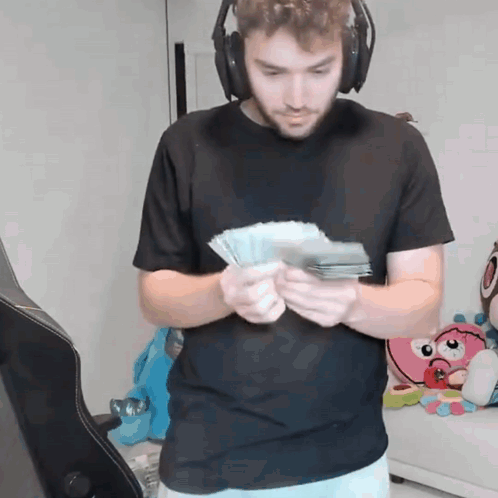 A Man Wearing Headphones Holds A Bunch Of Money GIF