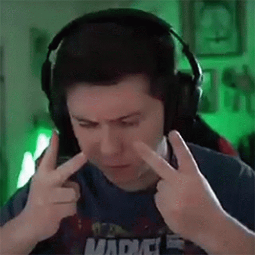 A Man Wearing Headphones Is Covering His Ears With His Hands While Making A Funny Face . GIF