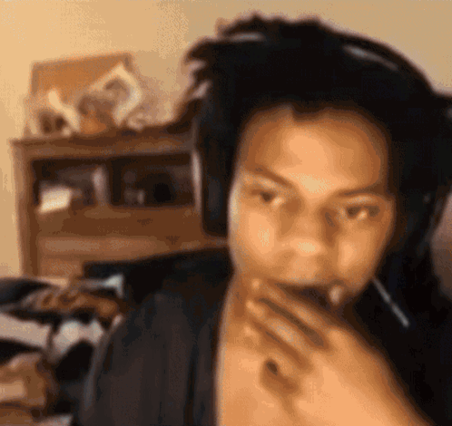 A Man Wearing Headphones Is Covering His Mouth With His Hand . GIF