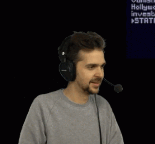A Man Wearing Headphones Is Dancing In Front Of A Screen That Says " Hollywood Invests " GIF