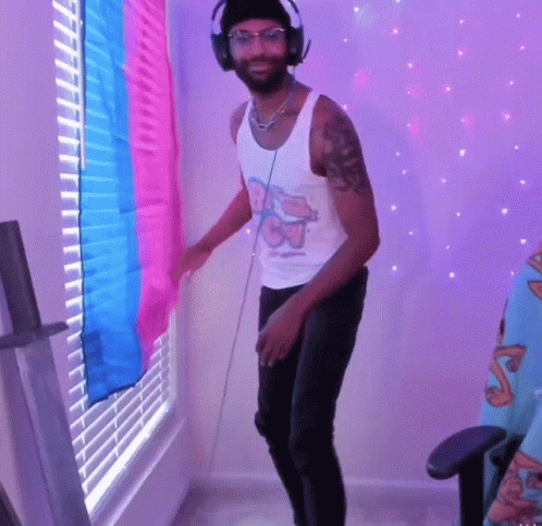 A Man Wearing Headphones Is Dancing In Front Of A Window With Blinds On It GIF
