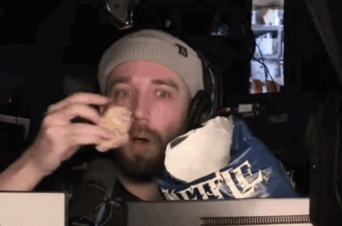 A Man Wearing Headphones Is Eating A Bag Of Kettle Corn Chips GIF