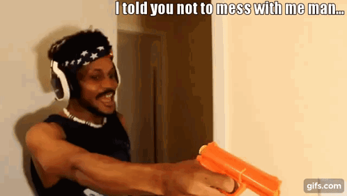 A Man Wearing Headphones Is Holding A Gun And Says " I Told You Not To Mess With Me Man ... " GIF