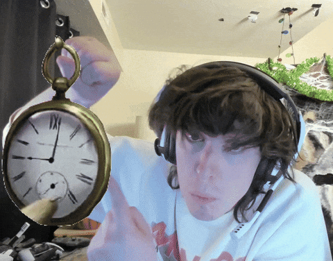 A Man Wearing Headphones Is Holding A Pocket Watch With Roman Numerals Including Xii On It GIF