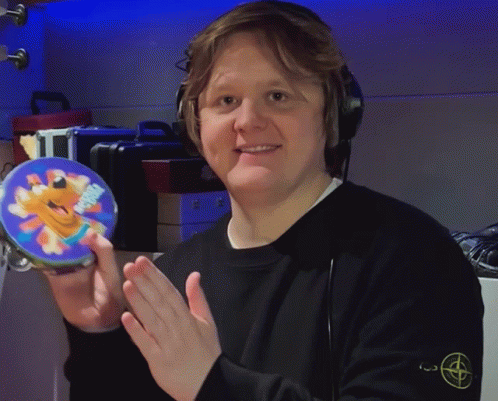 A Man Wearing Headphones Is Holding A Tambourine With A Picture Of A Cartoon Character On It GIF