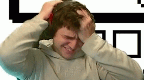A Man Wearing Headphones Is Holding His Head And Making A Funny Face . GIF