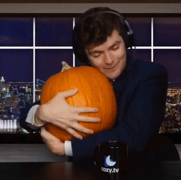 A Man Wearing Headphones Is Hugging A Pumpkin In Front Of A Cozy Tv Mug GIF