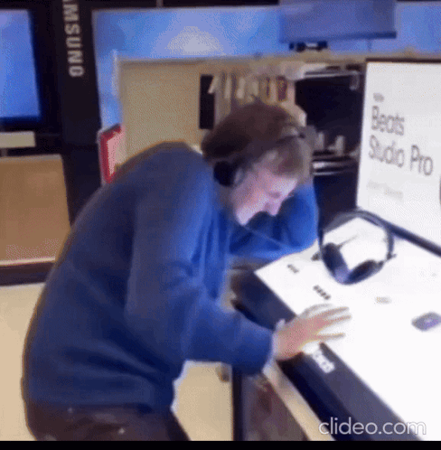 A Man Wearing Headphones Is Looking At A Beats Studio Pro Sign GIF