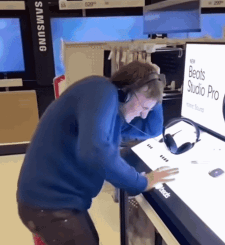 A Man Wearing Headphones Is Looking At A Display For Beats Studio Pro GIF