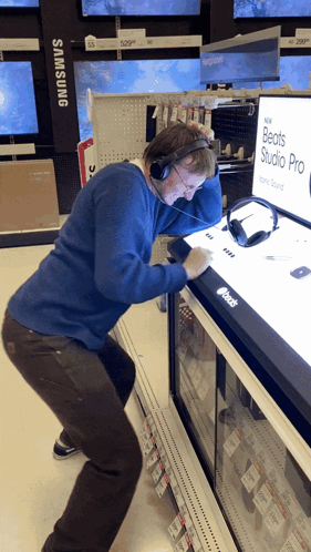 A Man Wearing Headphones Is Looking At A Display Of Beats Studio Pro Headphones GIF