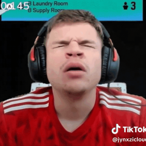 A Man Wearing Headphones Is Making A Face In Front Of A Laundry Room Sign GIF